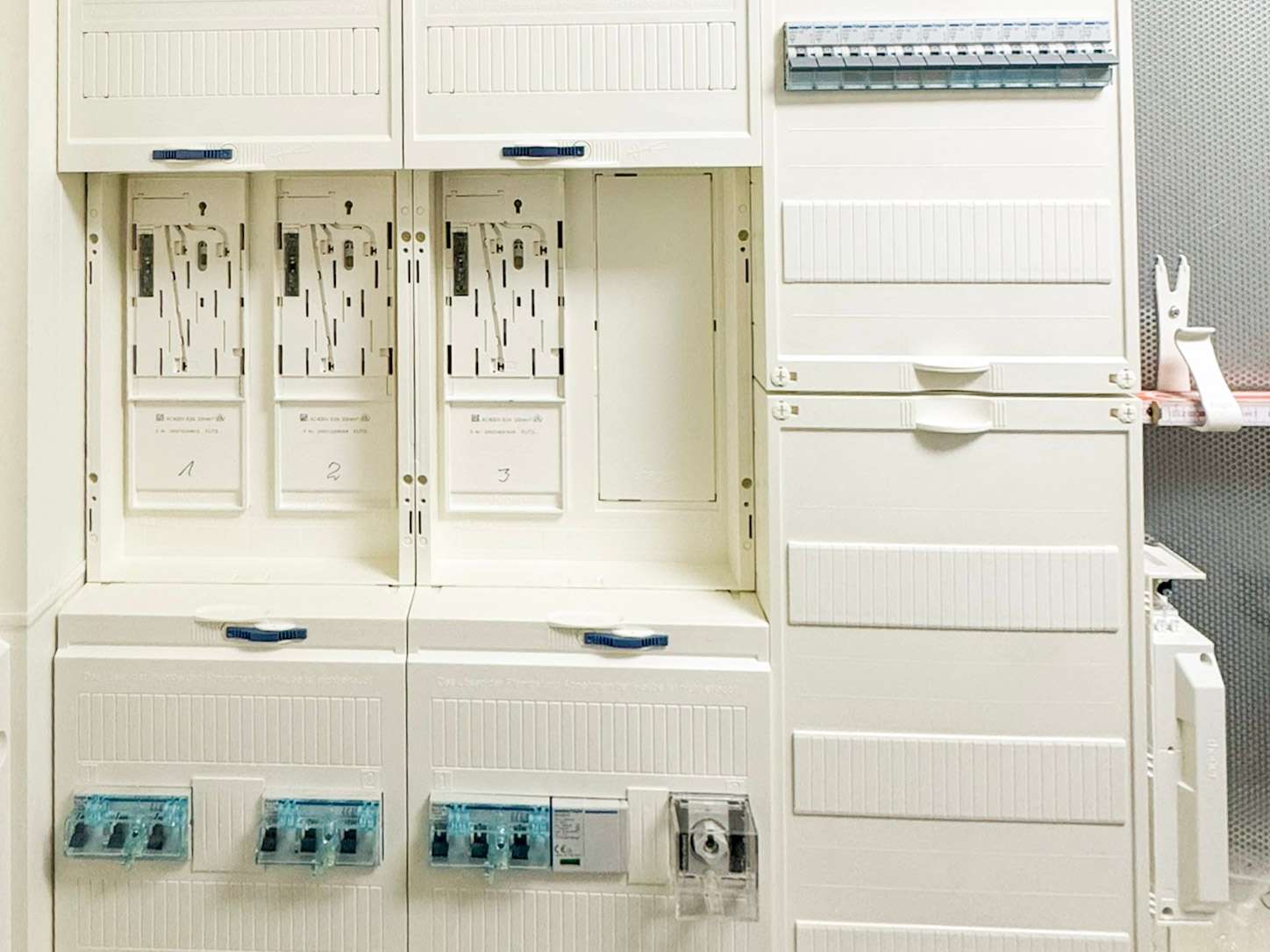 White electrical switchgear cabinets with multiple breakers and blue handles in a clean utility room.