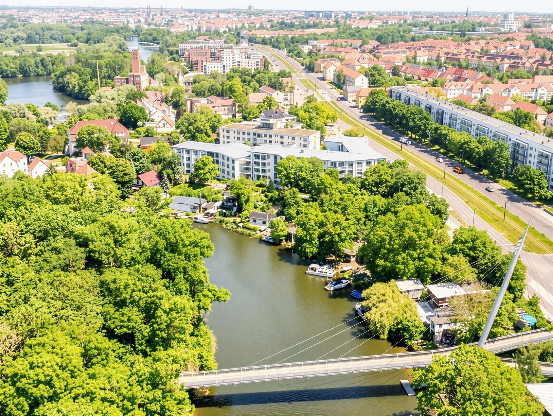 Aerial view of a river winding through a green city with bridges, red-roofed houses, and modern white apartment buildings.