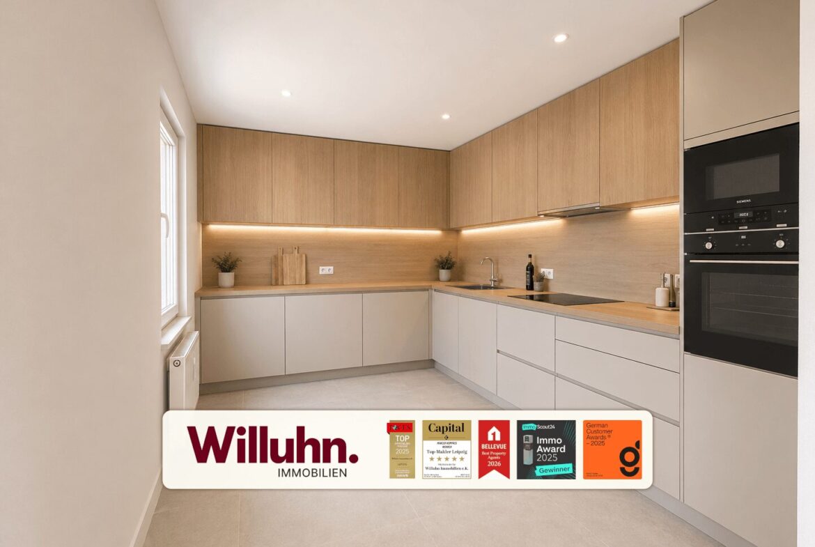Modern L-shaped kitchen with wood upper cabinets, gray lower cabinets, and under-cabinet lighting; built-in oven on the right.