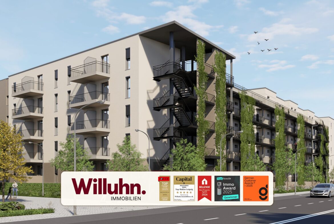 Modern beige apartment building with balconies and climbing greenery; a large Willuhn Immobilien sign with awards in front on the street side.
