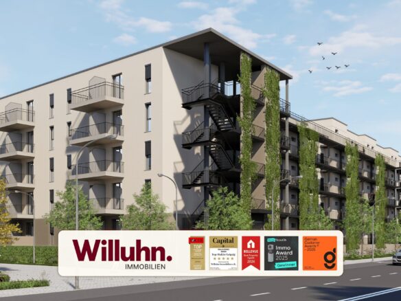 Modern beige apartment building with balconies and climbing greenery; a large Willuhn Immobilien sign with awards in front on the street side.