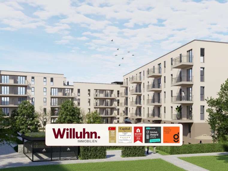Modern beige apartment complex with multiple balconies and a grassy courtyard; foreground shows a large Willuhn Immobilien sign.