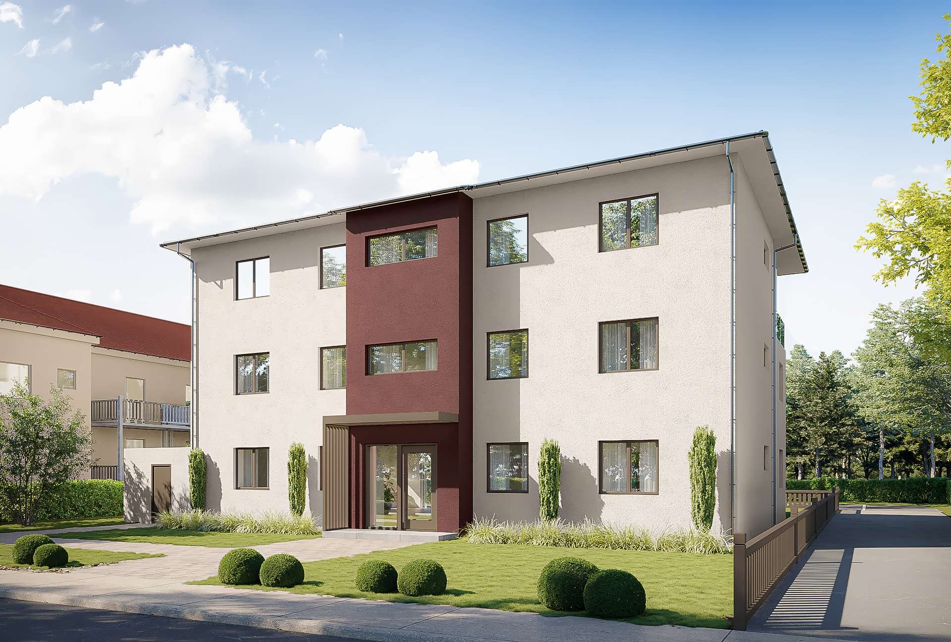 Modern apartment building with beige exterior and burgundy accent wall, green lawn, and trimmed shrubs in front.