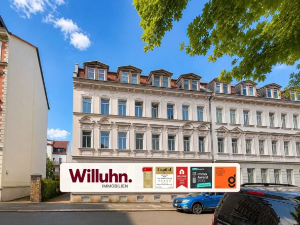 Facade of a classical white building under a bright blue sky with a large Willuhn Immobilien sign on the ground-floor storefront.
