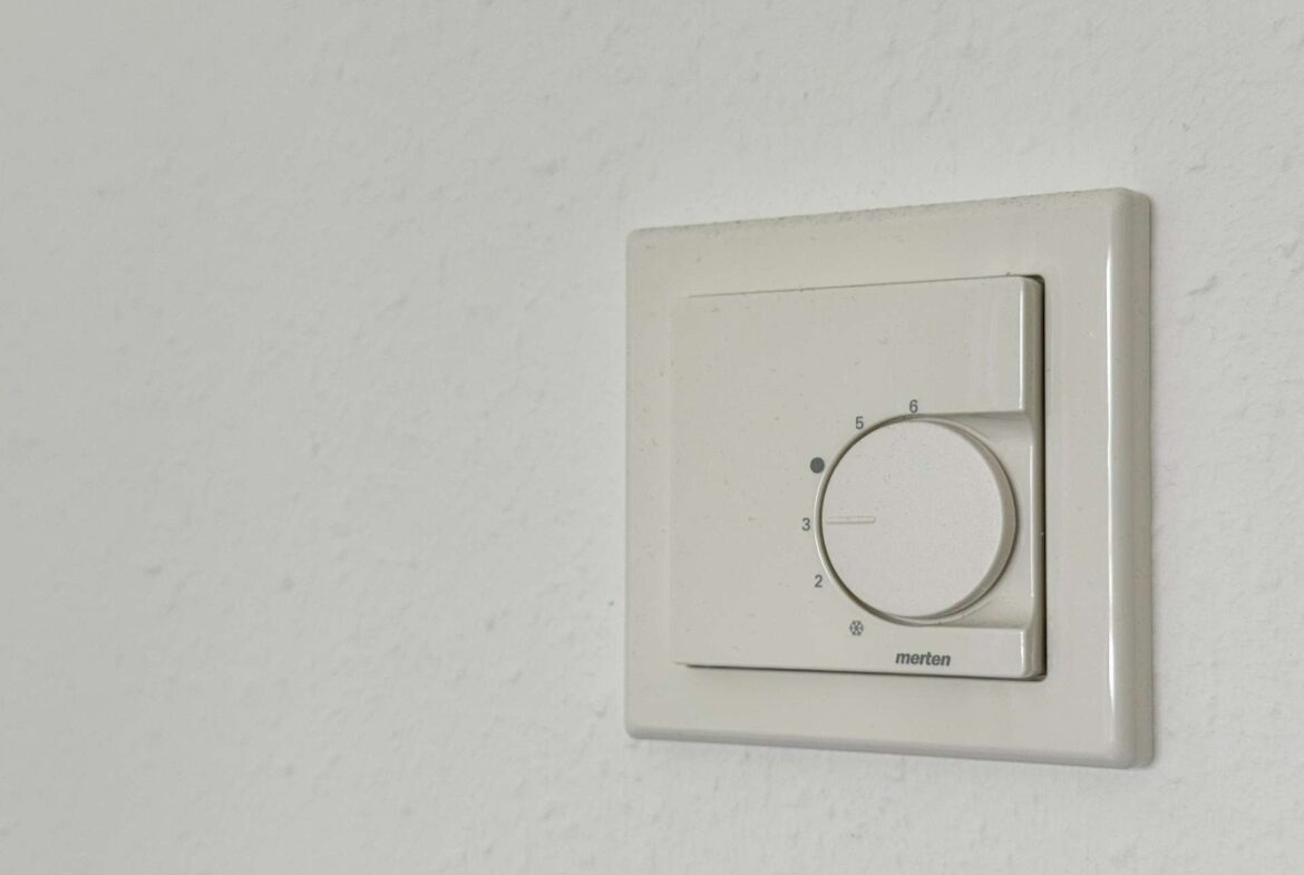 Close-up of a white rotary dimmer on a wall plate, used to adjust light level (numbers 2–6 visible).
