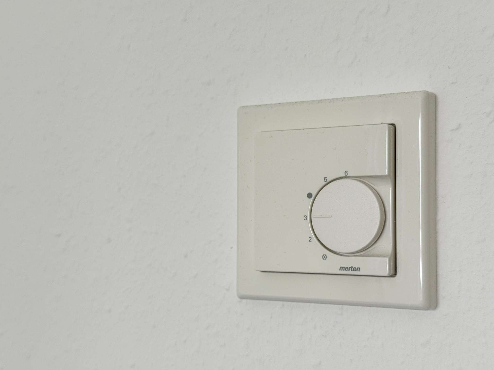 Close-up of a white rotary dimmer on a wall plate, used to adjust light level (numbers 2–6 visible).