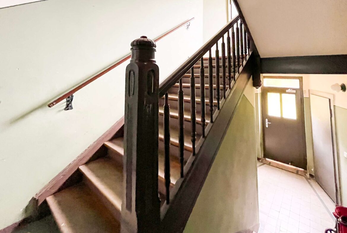 Indoor staircase with a dark wooden banister and spindles, green walls, and a door visible at the bottom right.
