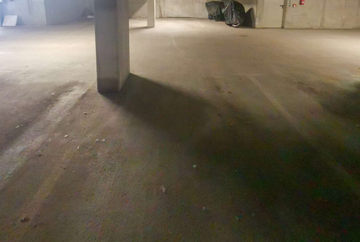 Dimly lit underground parking garage with a concrete pillar foreground and a covered scooter near wall 78–79–71 in background on the right side.