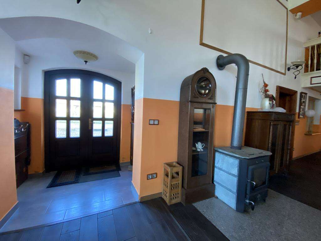 Entry hall with black arched double doors, peach walls, and a metal wood stove with a vertical flue.