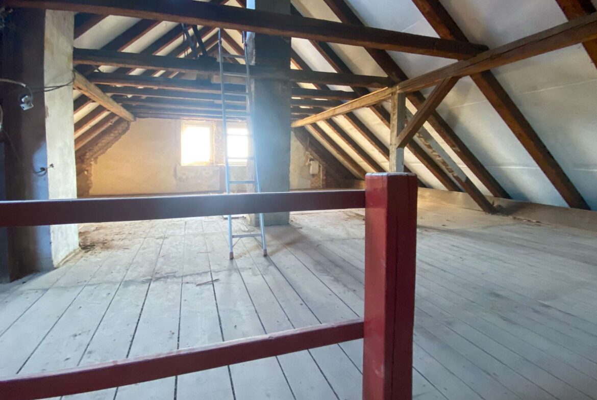 Dusty attic with exposed wooden beams, a red railing in the foreground, and a ladder by a bright window.