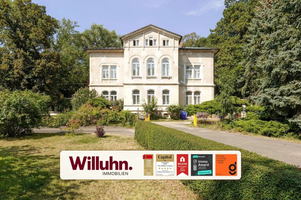 Beige two-story villa with arched windows, flanked by tall trees and a well-kept garden.