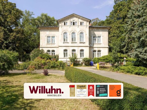 Beige two-story villa with arched windows, flanked by tall trees and a well-kept garden.