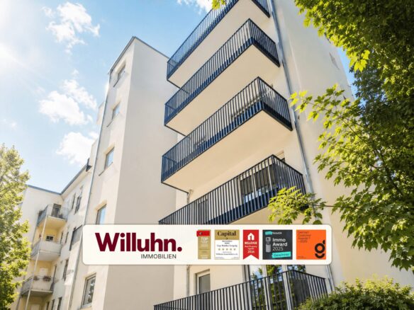 White apartment building with stacked blue rail balconies, sunny sky, and trees; a Willuhn Immobilien banner at the base.