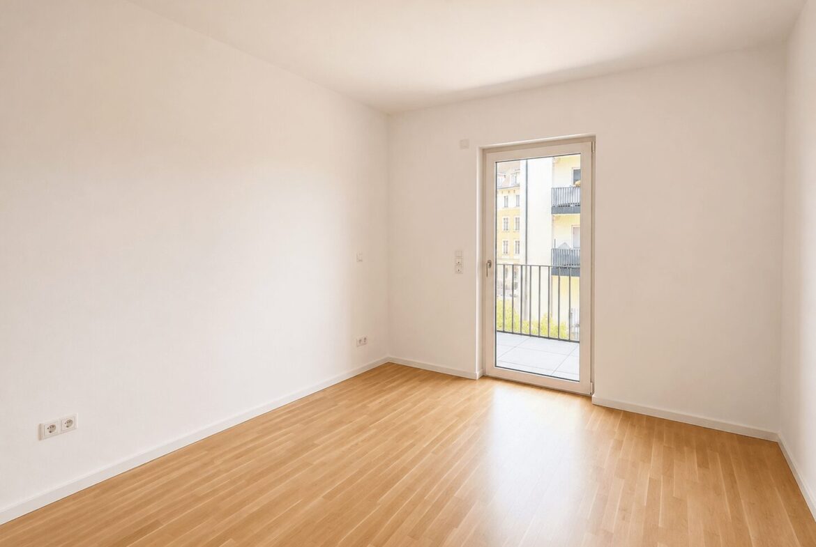 Empty white-walled room with light wood floor and a glass door opening to a small balcony with a metal railing outside.