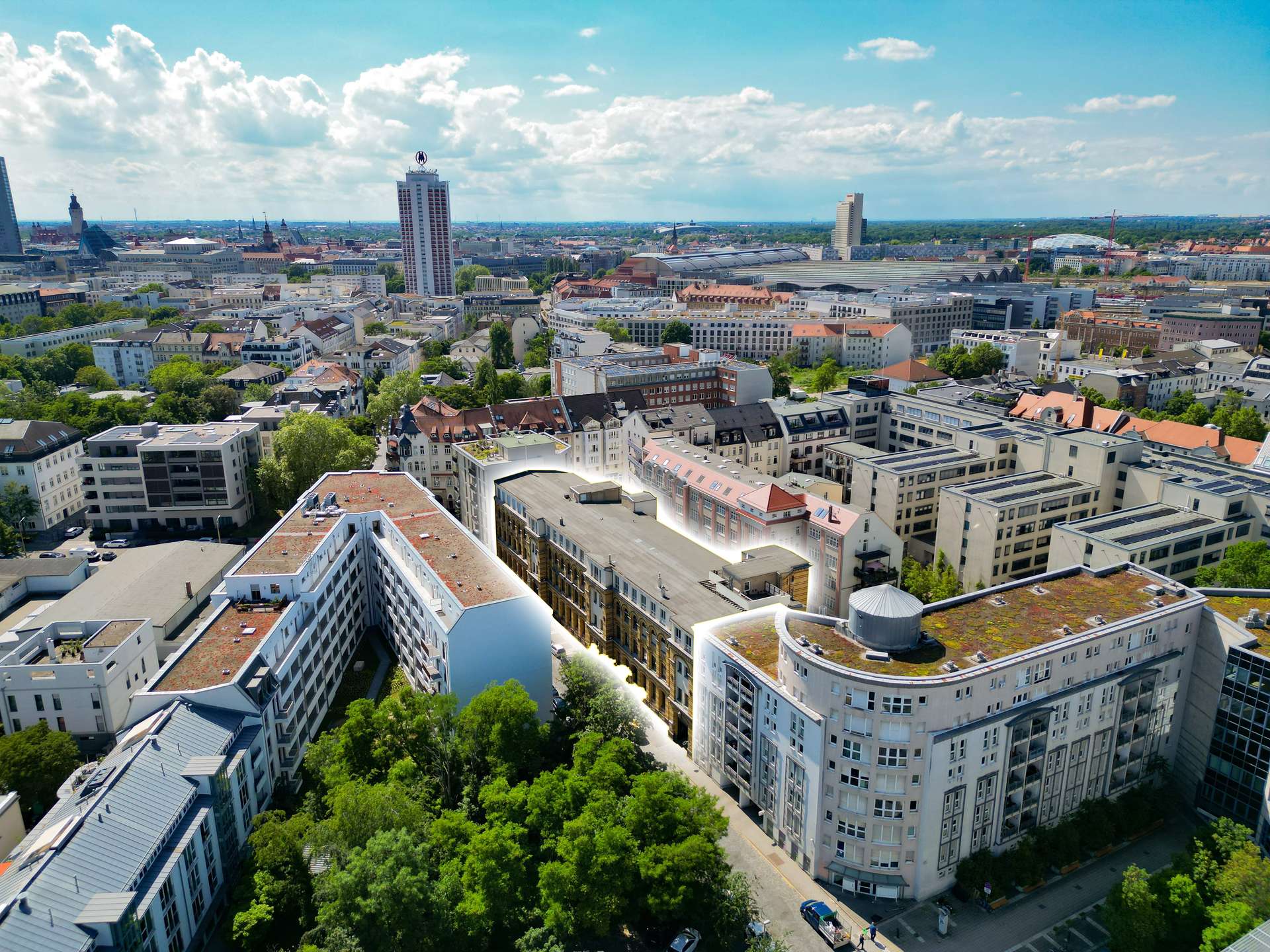 Aerial view of a dense cityscape with white modern apartment blocks, green trees, and a bright blue sky with scattered clouds.”,