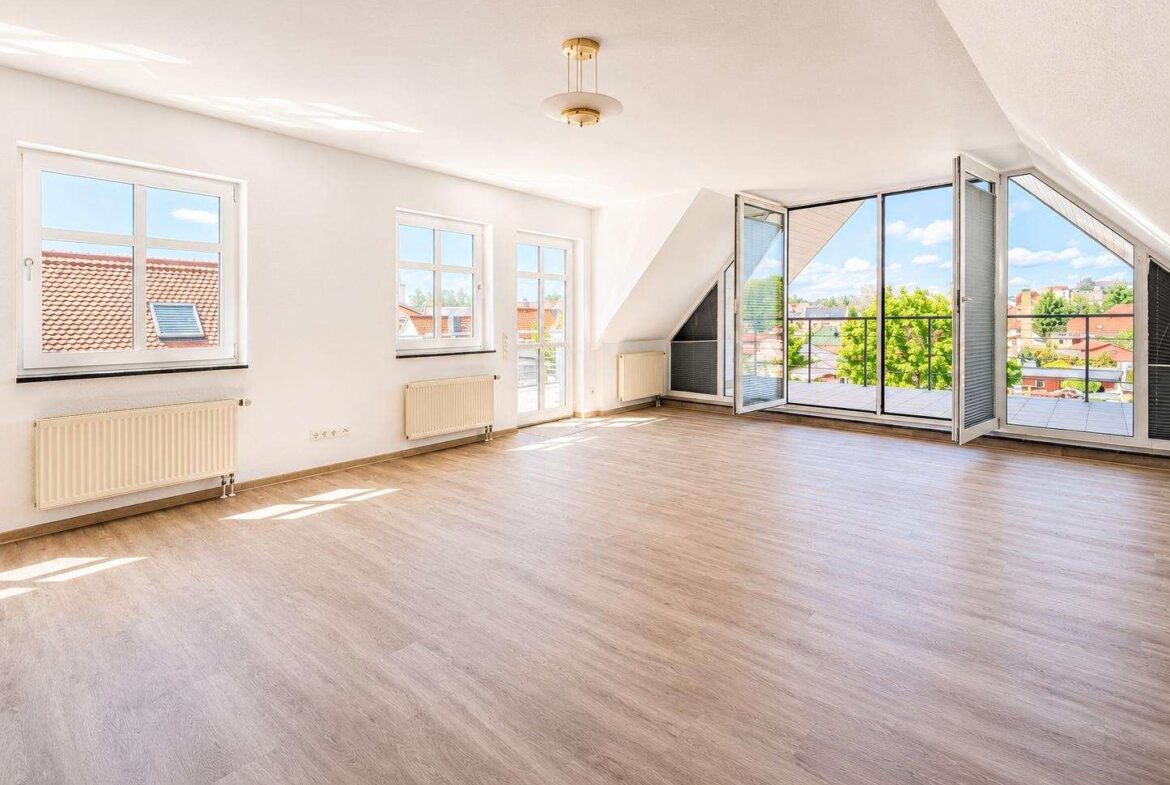 Bright empty living room with wide glass doors opening to a balcony and a sunny city view outside