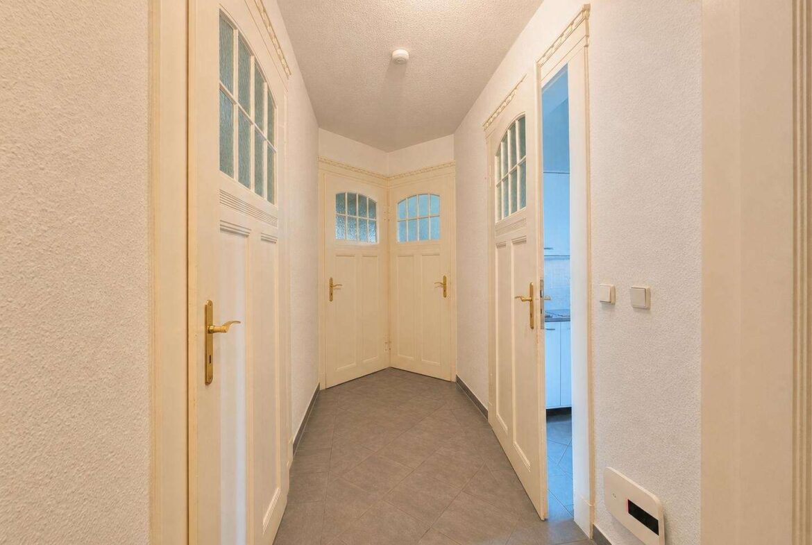 Bright hallway with white paneled doors and frosted glass windows along a tiled floor.