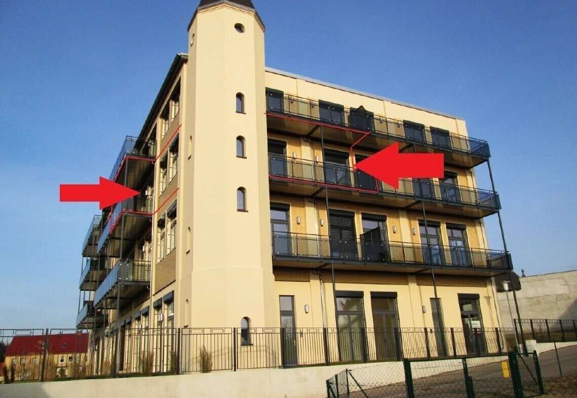 Beige multi-story apartment building with glass balconies; two red arrows point to the front balconies.