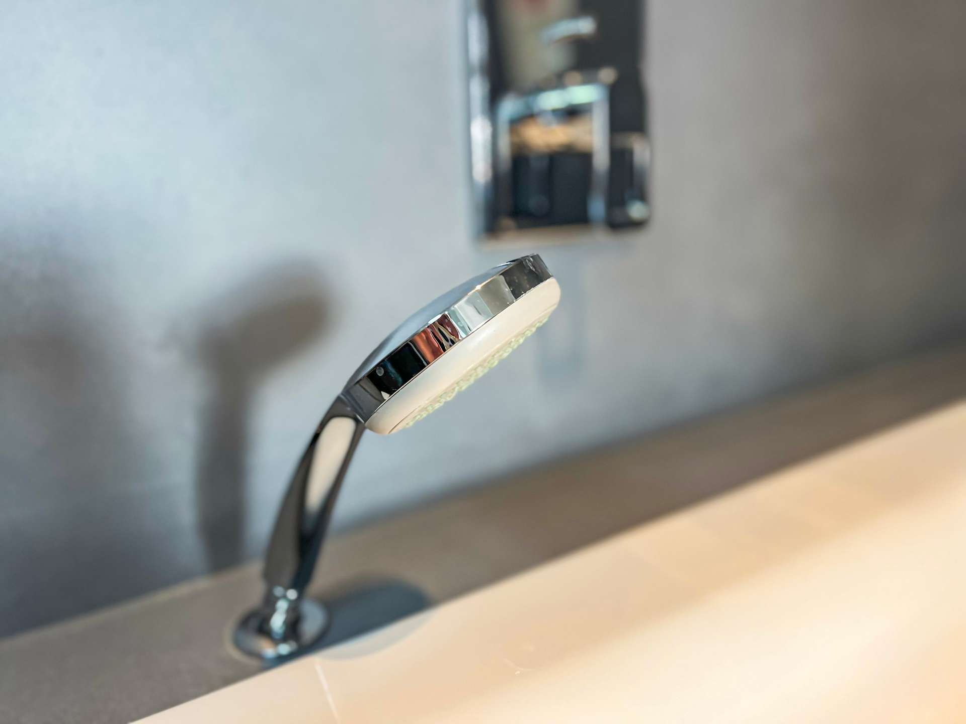 Close-up of a chrome faucet head over a sink with a blurred background, showing a sleek modern design.