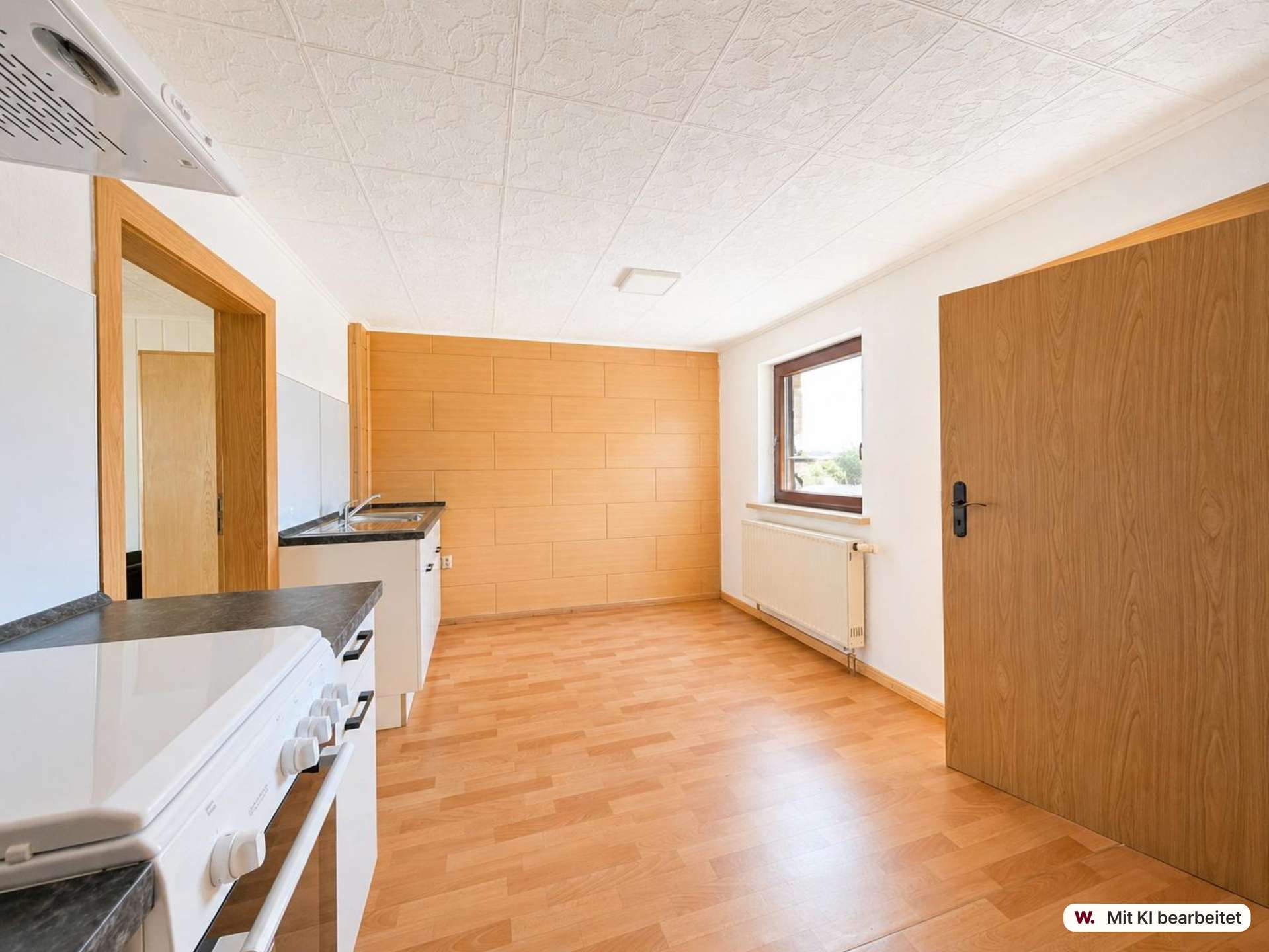 Bright kitchen with light wood cabinets, white appliances, and a large window bringing in natural light.