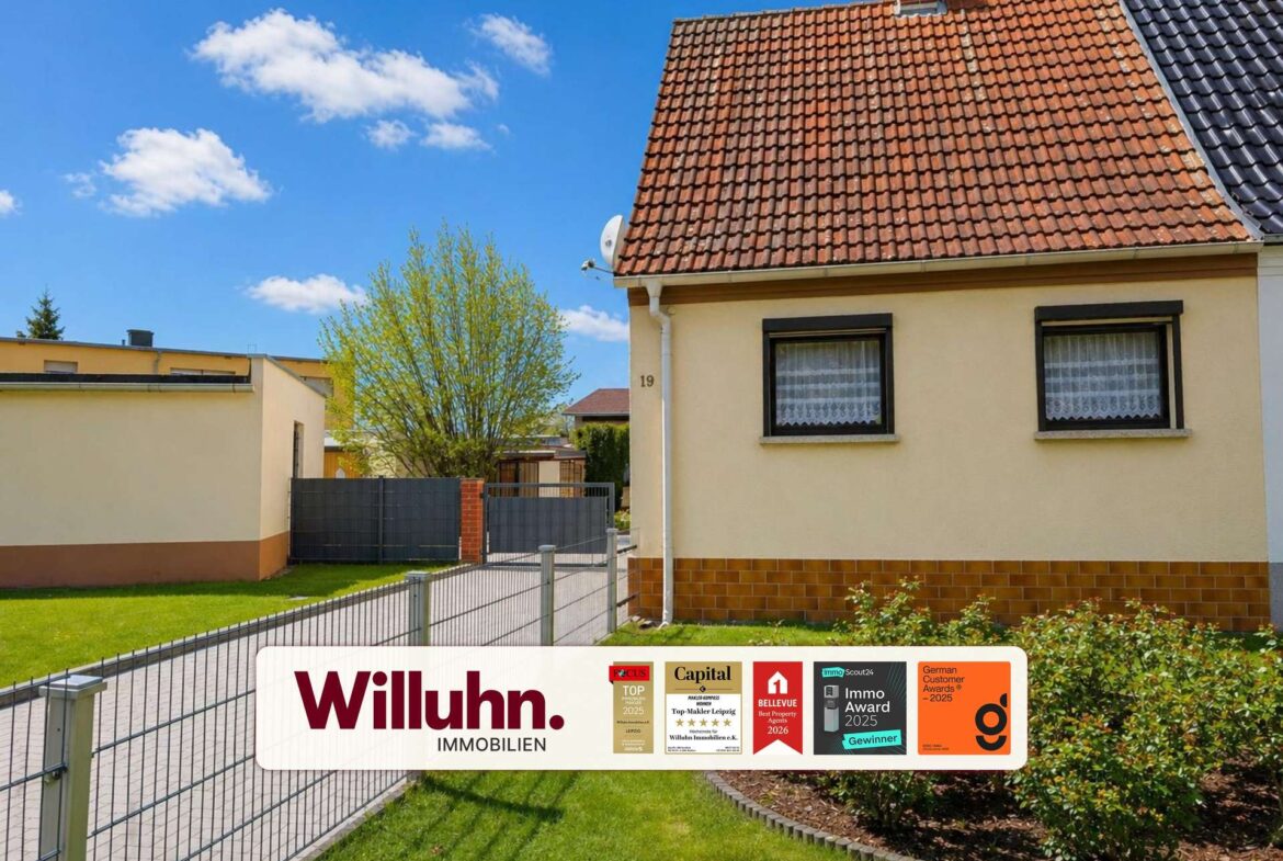 Residential property with red tiled roof, beige walls, and a Willuhn Immobilien sign in the front yard