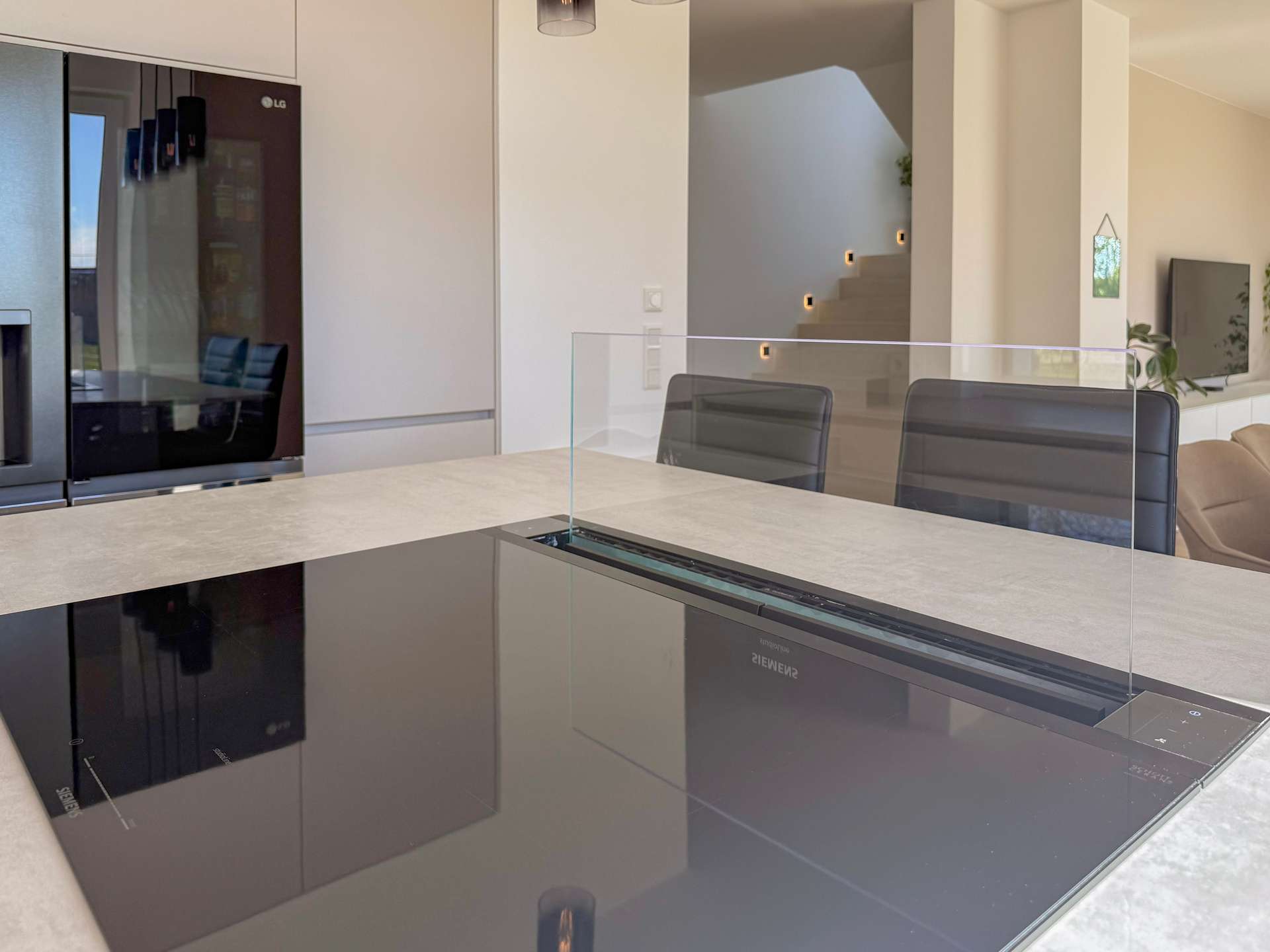 Contemporary kitchen with an island and a glass divider, stainless appliances, and light-colored surfaces.