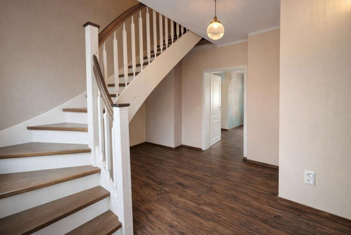 Foyer with dark wood floor, white staircase railing, and a hanging globe light above the staircase.