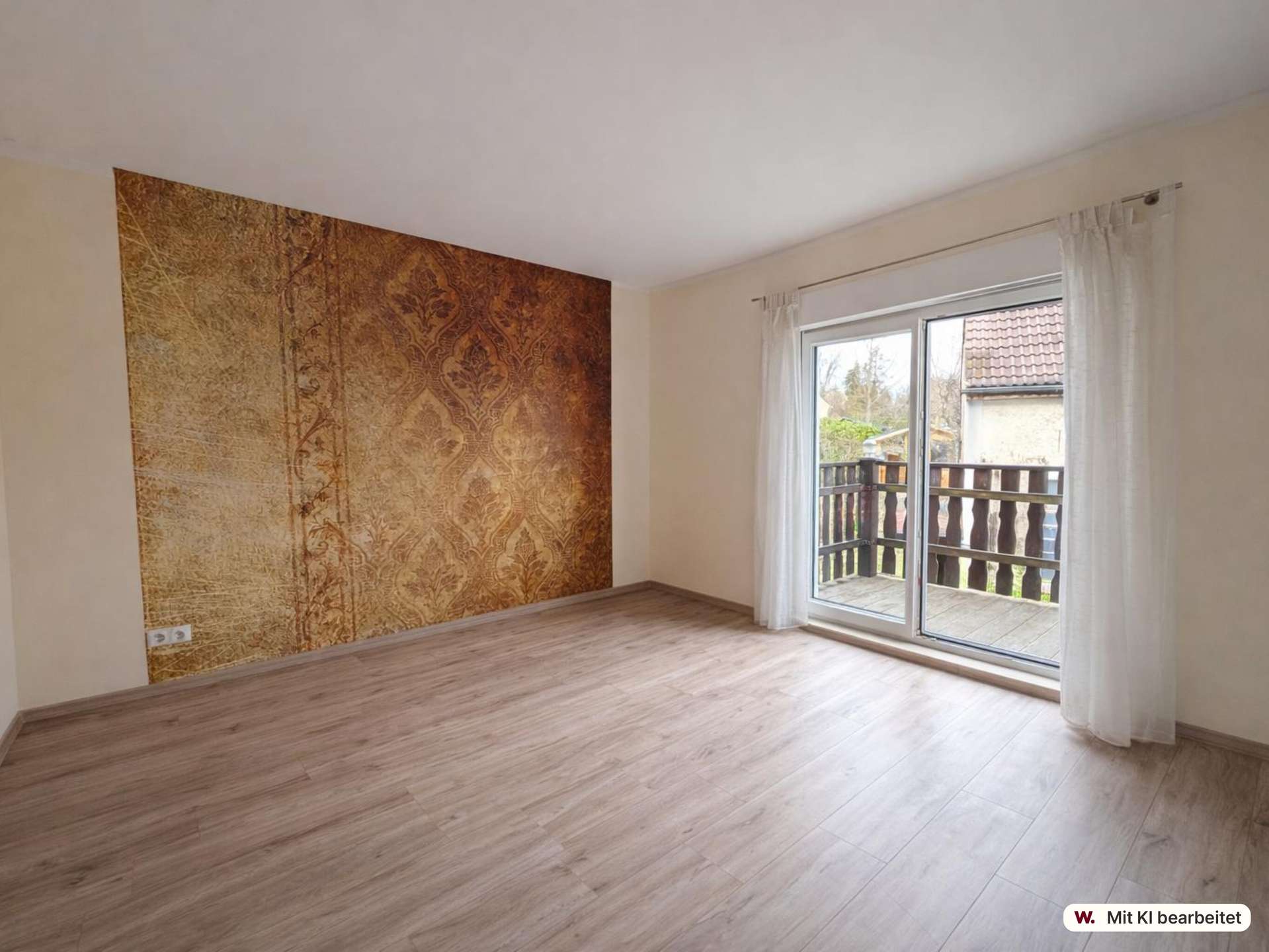 Bright empty living room with a brown ornate wallpaper accent wall, pale walls, light wood flooring, and sliding glass doors opening to a deck with white curtains.