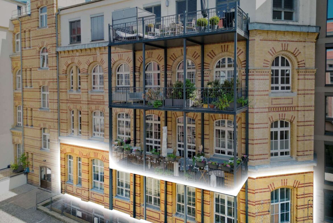 Brick apartment building with arched windows and a metal-framed balcony filled with chairs and potted plants on several levels