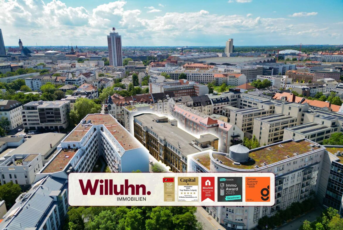 Aerial view of a European city with a large Willuhn Immobilien billboard across the bottom foreground, showing award logos.