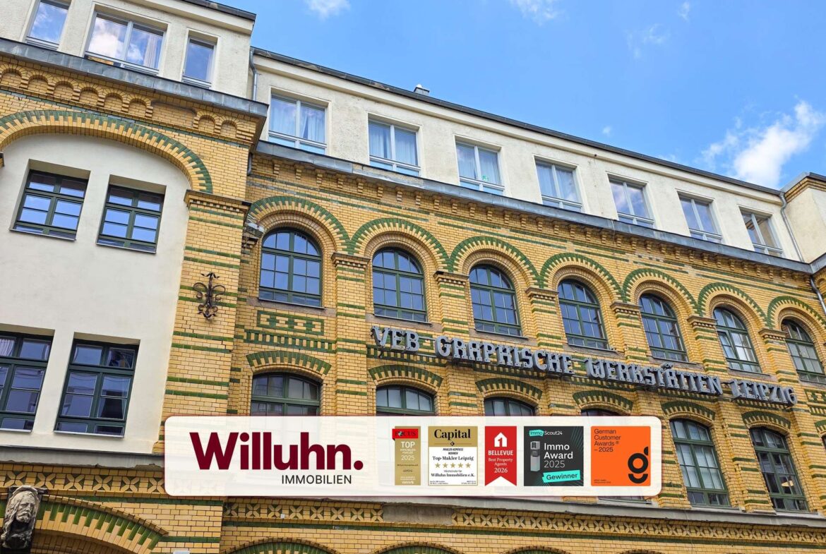Brick building with arched windows and a large Willuhn Immobilien banner across the storefront, indicating a real estate agency.
