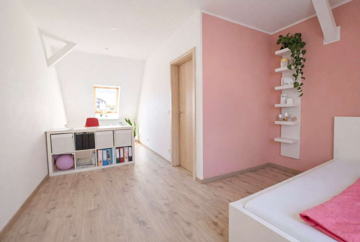 Bedroom with pink accent wall, white shelves and a low white bed visible at the edge, and a light wood floor.