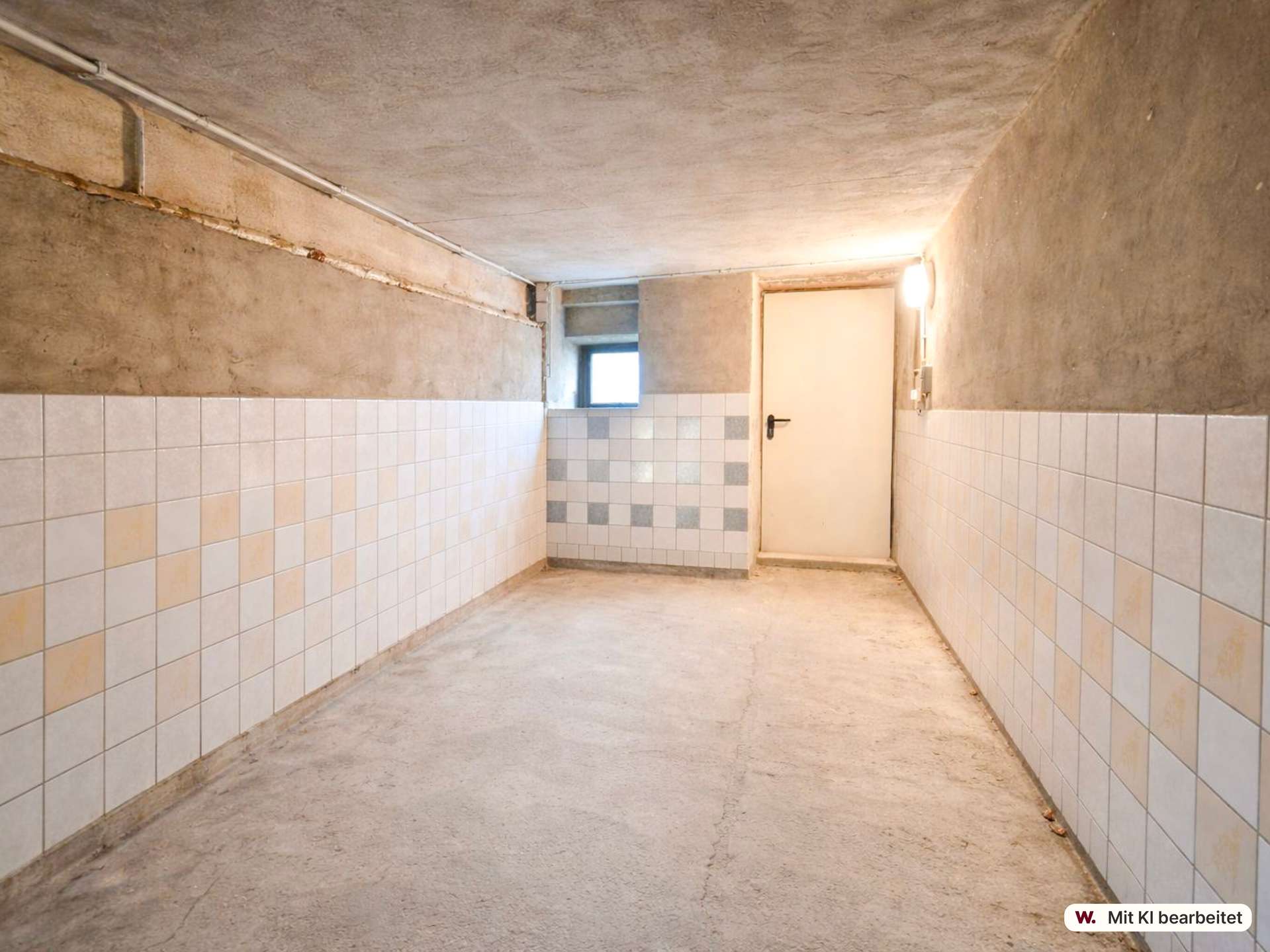 Basement hallway with tiled lower walls, a bare concrete floor and ceiling, a white door at the far end and a small window beside it.