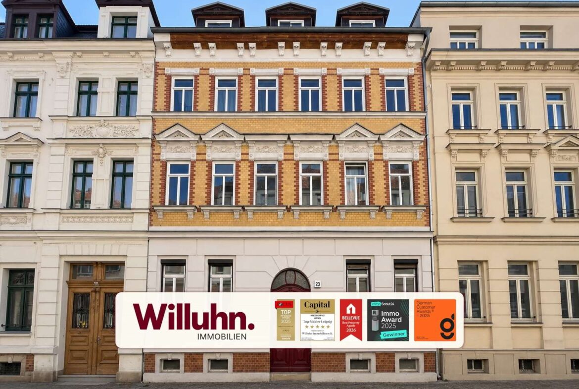 Facade of a row of historic buildings with a large 'Willuhn Immobilien' storefront sign and award plaques,